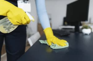 immagine ravvicinata di una donna che pulisce una scrivania di un ufficio con un panno