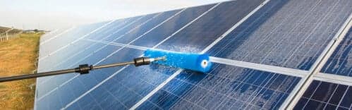 Una persona che pulisce un pannello fotovoltaico, con una spugna e un detergente, per mantenere l'efficienza dell'impianto fotovoltaico.