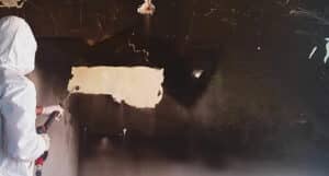 operatore che pulisce un muro da fuliggine dopo un incendio 